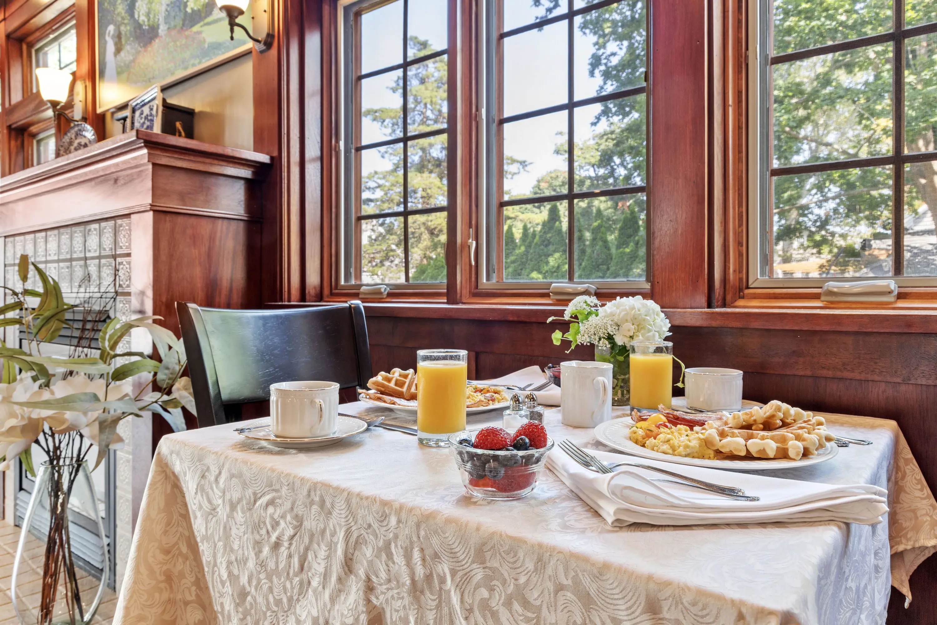 Elegant breakfast setup by a sunlit window with pastries and fresh juice.