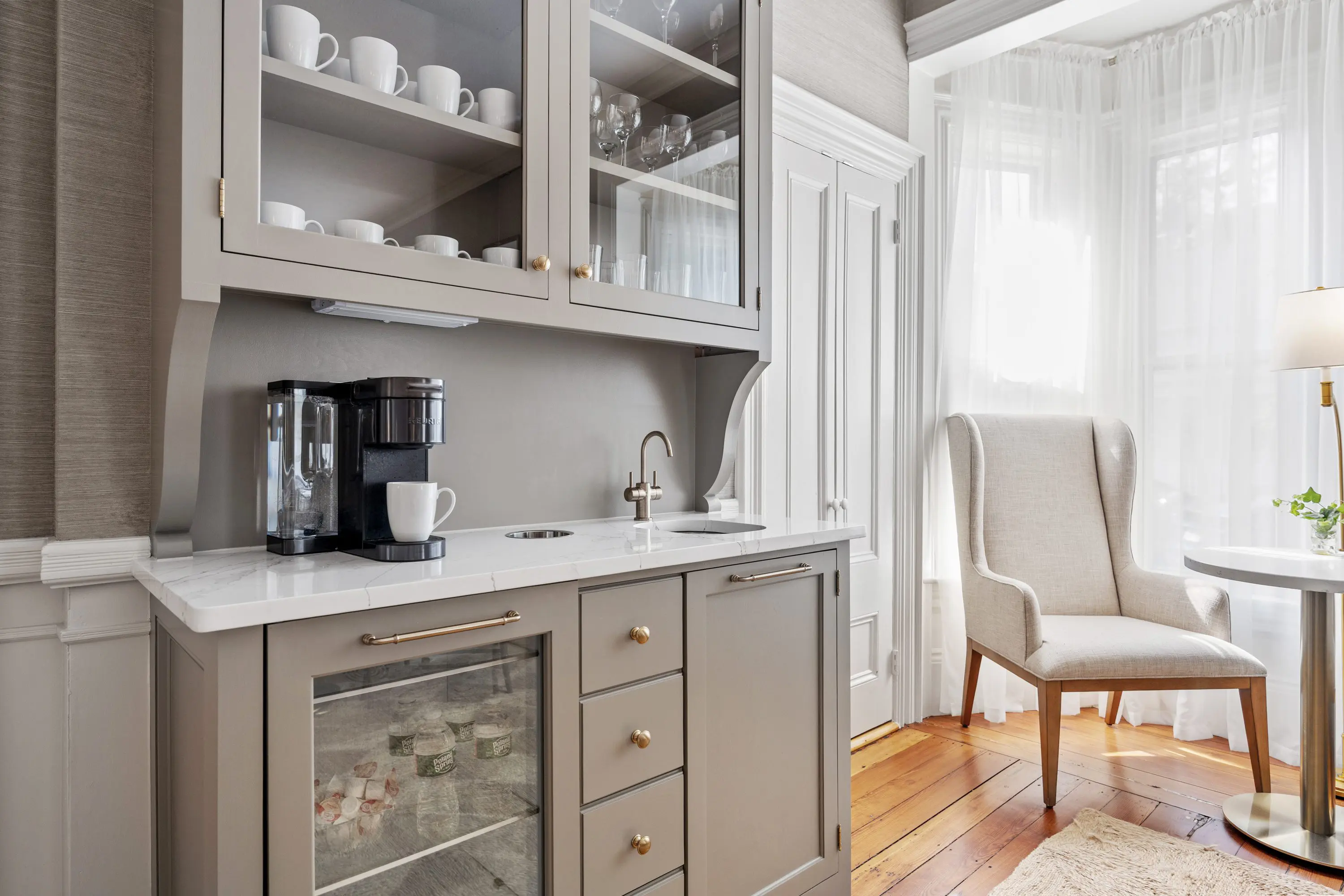 Cozy kitchen corner with coffee maker and glassware in neutral tones.