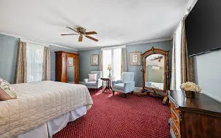 Cozy bedroom with vintage decor and red carpet.