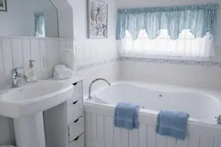 White bathroom with tub and blue accents.