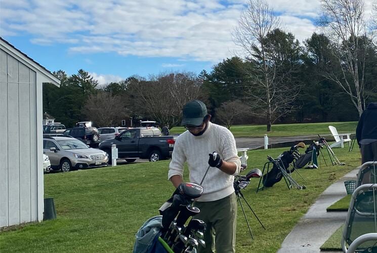 Person putting a golf club in a golf bag at a golf course